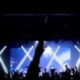 Blue-lit concert stage with crowd silhouettes at 0:01