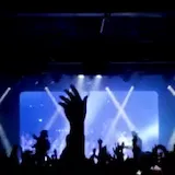 Blue-lit concert stage with crowd silhouettes at 0:06