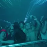 DJ plays live set under teal lasers at 0:38
