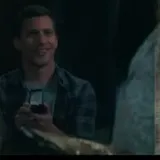 Man with camera smiles in dark scene at 0:07