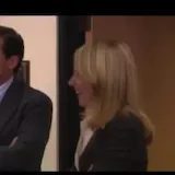 Office coworkers smiling and laughing in scene at 0:01
