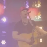 Singer in red cap performs live on stage at 0:40