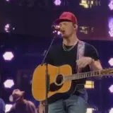 Singer in red cap performs live on stage at 0:01