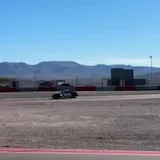 Handheld footage of cars on desert race track at 0:09
