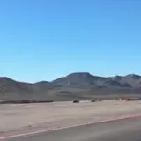 Handheld footage of cars on desert race track at 0:01