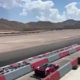Red sports car laps desert racetrack at 0:02