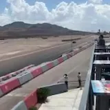 Red sports car laps desert racetrack at 0:08