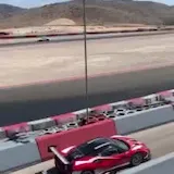 Red sports car laps desert racetrack at 0:01