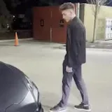 Man walks past dark sports car at night at 0:01