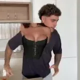 A creator in a corset pours a drink and plays blackjack in a skit at 0:06