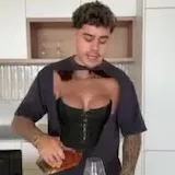 A creator in a corset pours a drink and plays blackjack in a skit at 0:01