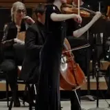 María Dueñas plays Chant de la Veslemøy on violin in a green courtyard at 0:35