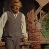 A man steps out of a hut in Wicker, greets his friends and calls at 0:01