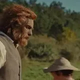 A man steps out of a hut in Wicker, greets his friends and calls at 0:22