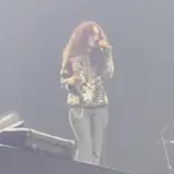 Singer performing live on arena stage at 0:10