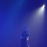 Estevie performing on blue-lit concert stage at 0:09